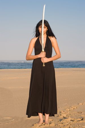 Asian model posing with a sword against blue skyの写真素材