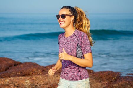Cardio running workout of young beautiful woman warm up jogging on beach, fitness slim body, healthy...