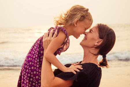 happy family at the beach. mother hugging child daughter and fly tourism with children.spf and...