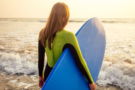 active women with surf board enjoy watersport at vacation holidays.sport girl in surfing school instructor of windsurf. tourist female model in a diving suit wetsuit on the beach in the Indian Oceanの写真素材