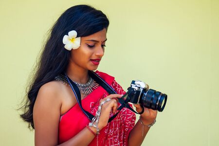 Female India photographer photographing with digital camera on the beach.beautiful indian woman in red traditional sari in the tropical paradise sea taking pictures of the landscape photo shootの写真素材