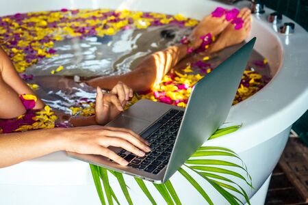 freelancing and remote work.beautiful girl working with laptop while lying in a bathtub with...