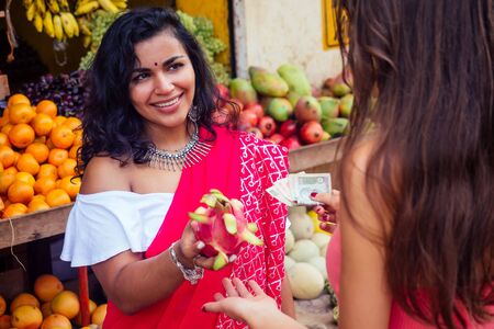 travel girl seller in street market and a buyer in a fruit shop in india.の写真素材