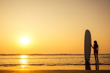 copy space silhouette of a young fitness female model at sunset on the beach summer sea.freelancer woman resting surfing the summer ocean copyspaceの写真素材