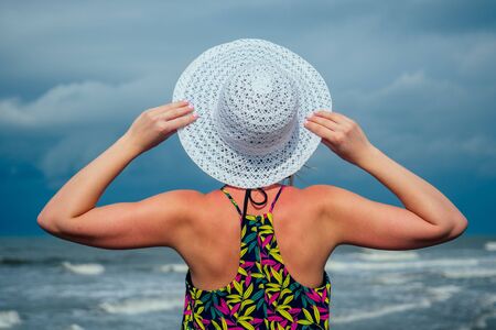 woman in a white hat looks at the sea