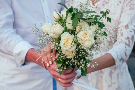 a bouquet of a bride from white roses in the hands of the newlywedsの写真素材