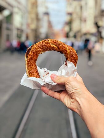Turkish bagel SIMIT in white hand on street
