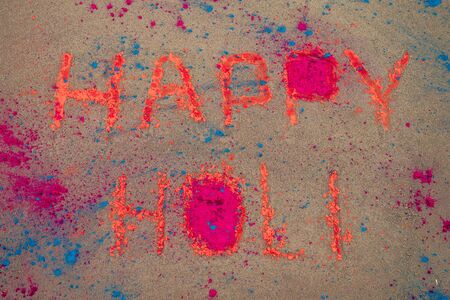 Happy Holi inscription on the sand blue and orange dust holy