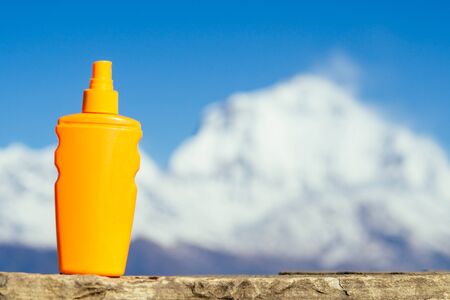 sunscreen in an orange bottle on a mountain background. the concept of preventing skin cancer and the use of sunscreen in the mountains.の写真素材