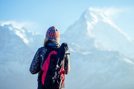 a young tourist woman with a hiking backpack and a knitted hat in the Himalaya mountains. trekking...