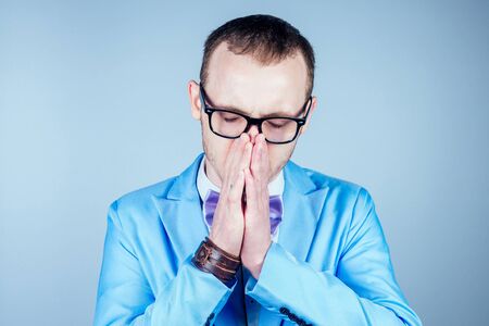 portrait of a young male nerd in glasses and in a stylish suit holds a hand near the head. concept of headache and intellectの写真素材