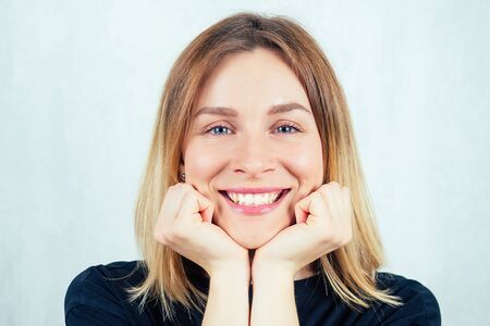 Portrait of a young and beautiful blonde woman smiling with a broad smile in a black T-shirt.
