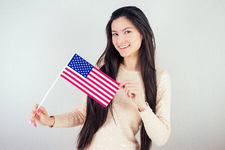 beautiful girl in a white blouse holding an American flag on a white background. The concept of Americas Independence Dayの写真素材