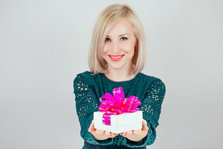 attractive blonde woman in green dress gives bright boxes with gifts. holiday concept