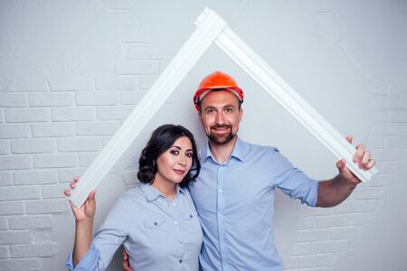 happy family handsome man in the construction helmet hardhat and charming woman together are...