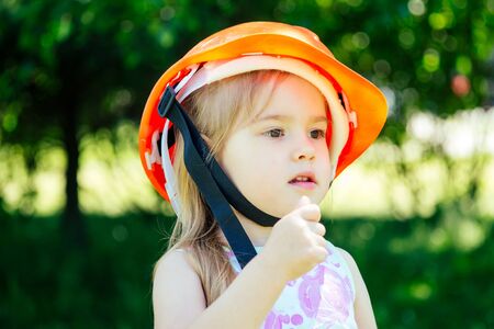 little girl builder in construction hardhat helmet on green park backgroundの写真素材