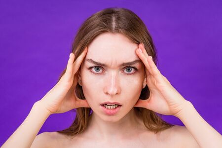 portrait of a beautiful stress woman headache on purple background in studio