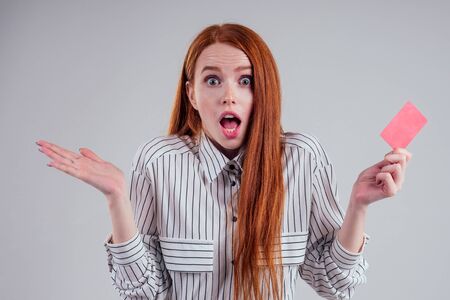 surprised and amazed attractive spender redhead caucasian businesswoman wearing striped shirt...