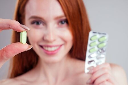 redheired ginger woman with one pack of happy pills thinking white background studio.の写真素材