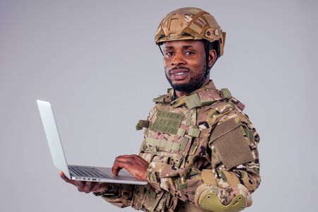 African American soldier smiles while typing a computer videocall with wife and childの写真素材