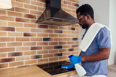 african man cleaning cooktop cooker hood at home ,Brick wall background