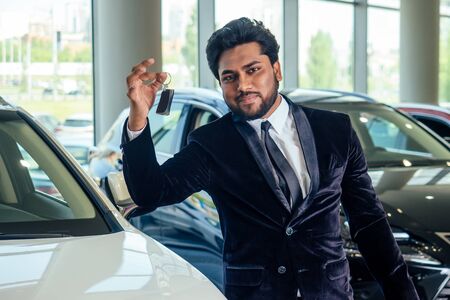happy business indian man in well-dressed black suit buy new biodiesel eco automobile in lux showroomの写真素材