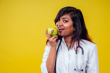 Female indian young and beautiful blond woman gynecologist doctor using stethoscope holding a green...