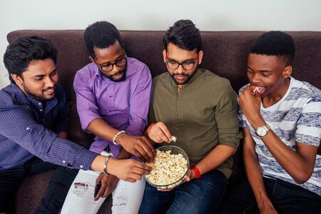 four african american males eating pizza at home party,throwing popcorn into each otherの写真素材