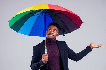 smiling businessman in suit coat wool with multi-coloured umbrella white background studioの写真素材