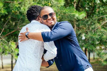 two stylish young friends hugging long-awaited meeting in street parking