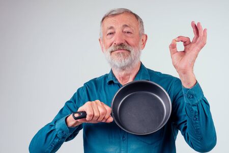 man old holding frying metal non-stick pan in studio white backgroundの写真素材