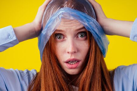 beautiful redhaired ginger stylish woman wearing red plastic polyethylene package on her head and...