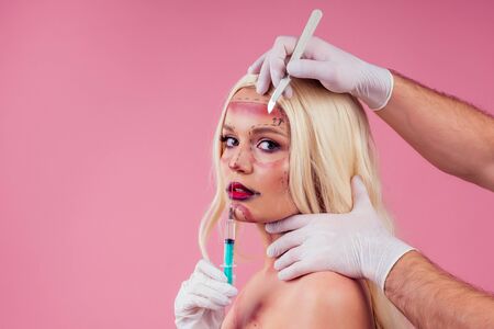 parody of beautiful perfection victim fashion woman with surgery njection and surgeon scalpel.halloween makeup greasepaintの写真素材