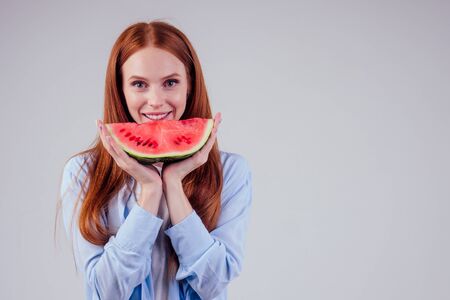 redhaired ginger girl with big piece of watermelon in studio white background.detox yoga conceptの写真素材