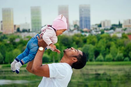 afro father hugging her mixed race daughter spending time in garden.の写真素材
