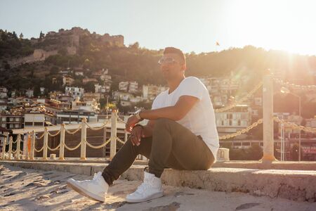 Fashion rich Arab man wear sunglasses and white t-short posed against arabian sea.の写真素材