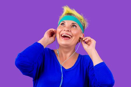 happy old cheerful female and a blue bandage on forehead, listen yoga mantra meditation song on...