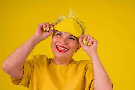 mature woman with colored stylish yellow dyed hair in warm dress with sleeping mask on her eyes background studio copy spaseの写真素材