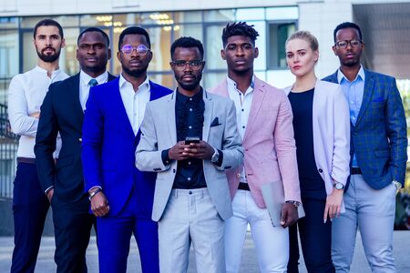 a group of seven successful business people men and woman in stylish suits standing and looking proudly outdoors . teamwork and the multiethnic company conceptの写真素材