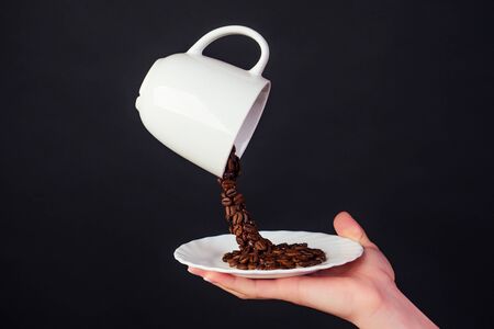 Magic coffee bean splash from a cup with plate in black background.