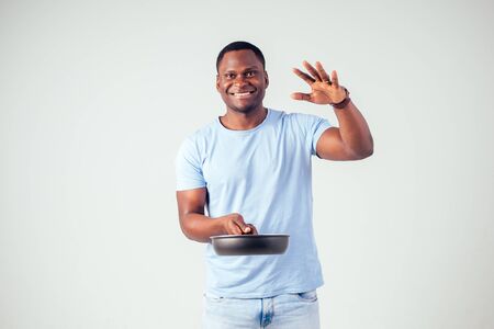 african american chef kitchener holding a frying pan wizard man cooking magic flying food salad, carrot, garlic, onion, pepper, potato, cucumber isolate white background studio.magic of taste fantasyの写真素材