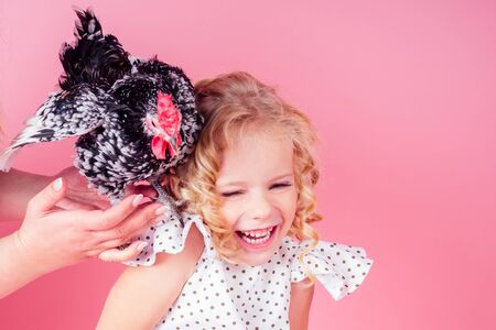Cute little blonde girl with a cock easter in studio pink background.beautiful female kid...