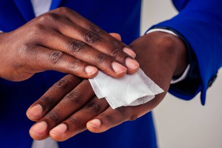 successful and beautiful American afro man in a business suit in a white shirt using wet wipesの写真素材