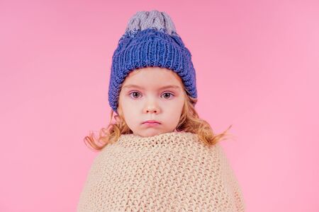 portrait of unhappy little girl wearing knitted scarf and sweater and scarf. Child getting sick flu...