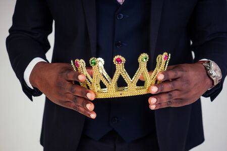 Confident businessman business king in a black classic suit with a tie and glasses put on a crown on...