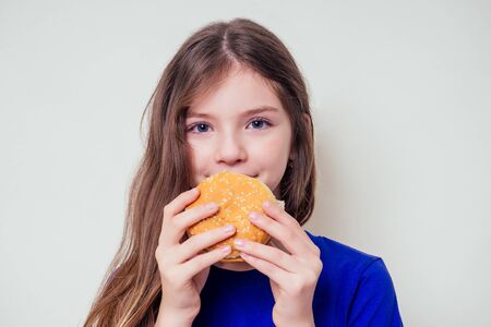 beautiful teenager girl is eating baked vegetarian burger with vegetables. Child vegan idea healthy eating concept.clear skin perfect teen acne refusal from junk foodの写真素材