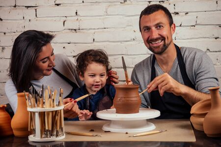 Father , mother and son clay bowl working in pottery workshop traditional arts . family business handmade shop spend holiday together in art studio. young talented artist and parentsの写真素材