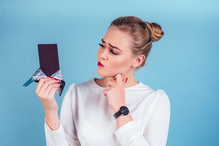 Portrait of beautiful business woman holding chocolate bar blue background in studio