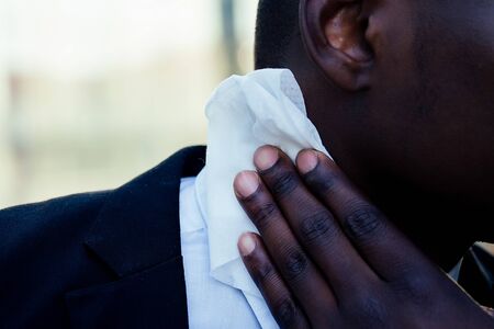 successful and beautiful American afro man in a dark business suit in a white shirt using wet wipesの写真素材