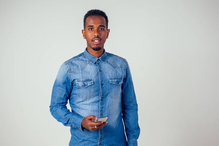 Afro american young holding phone in studio on white backgroundの写真素材